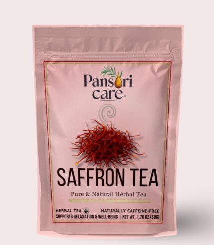 Pansari Care Saffron Tea in a clear glass teacup, with saffron threads floating in the golden liquid and a pile of saffron on the side.